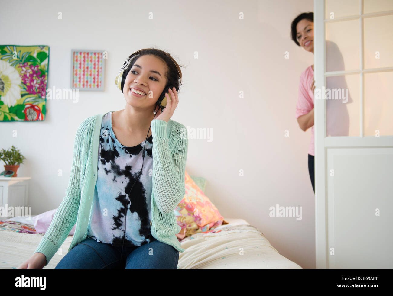Madre controllo sulla ragazza adolescente ascoltando le cuffie Foto Stock