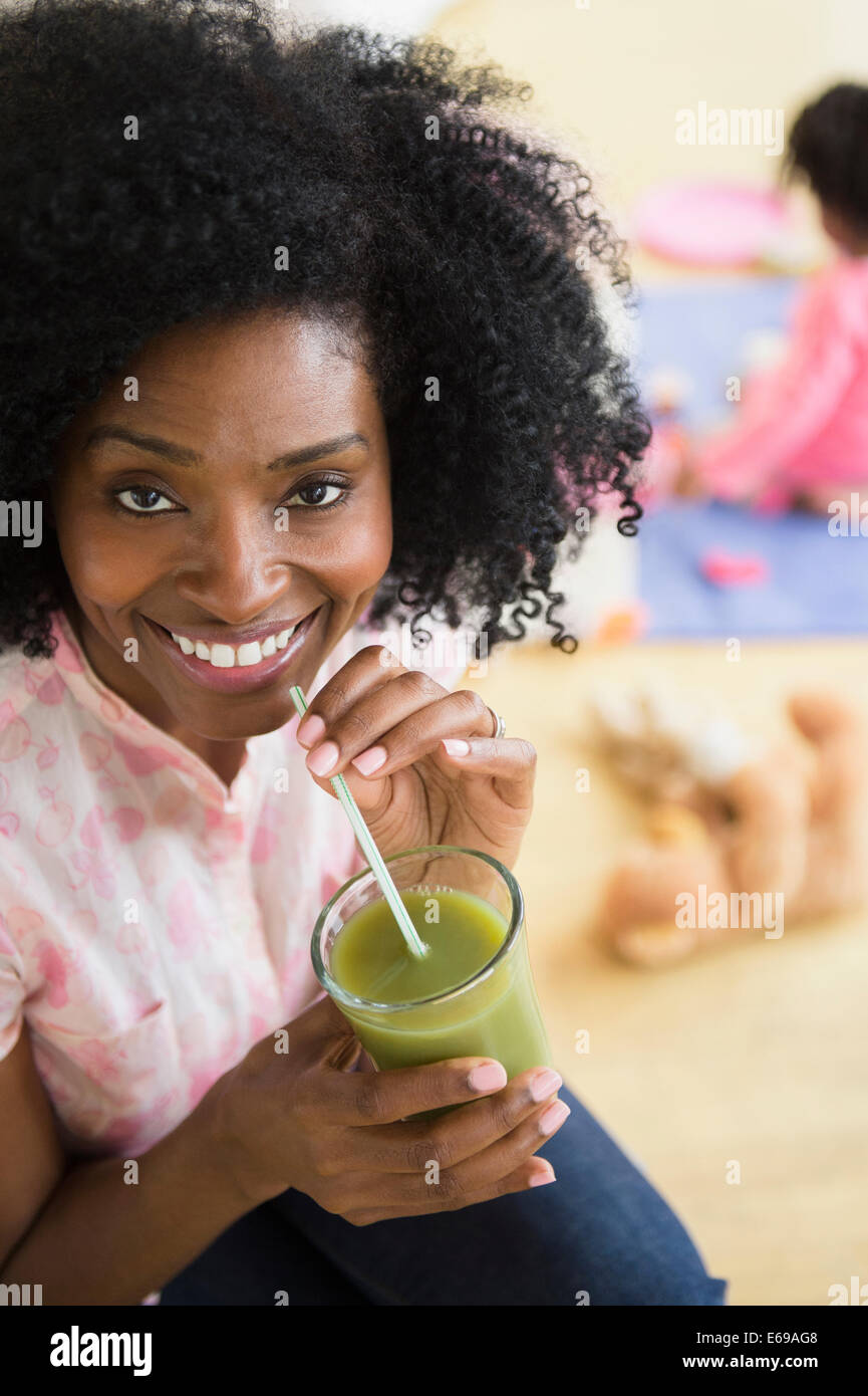 Donna sorridente di bere succo verde Foto Stock
