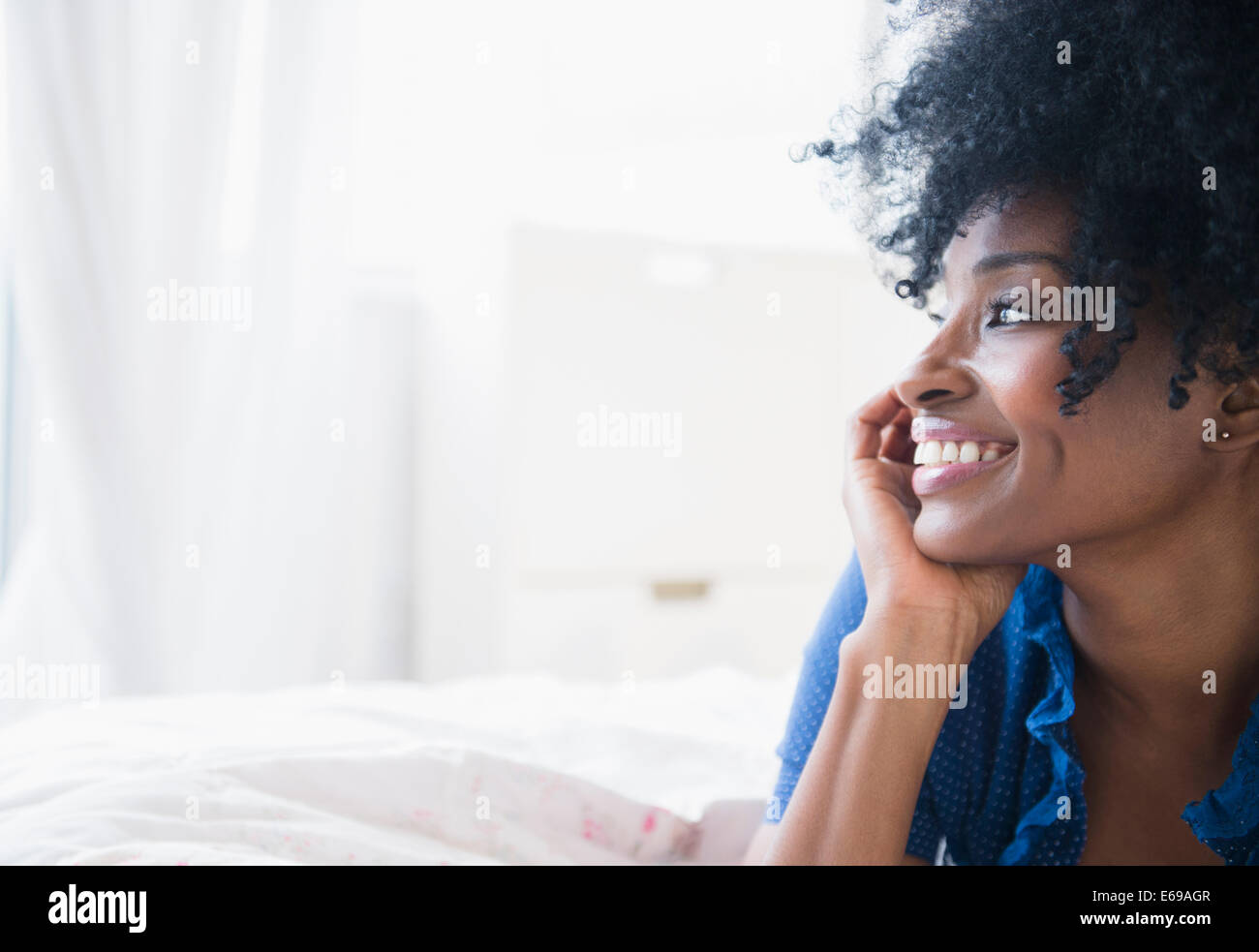 Nero donna sorridente sul letto Foto Stock