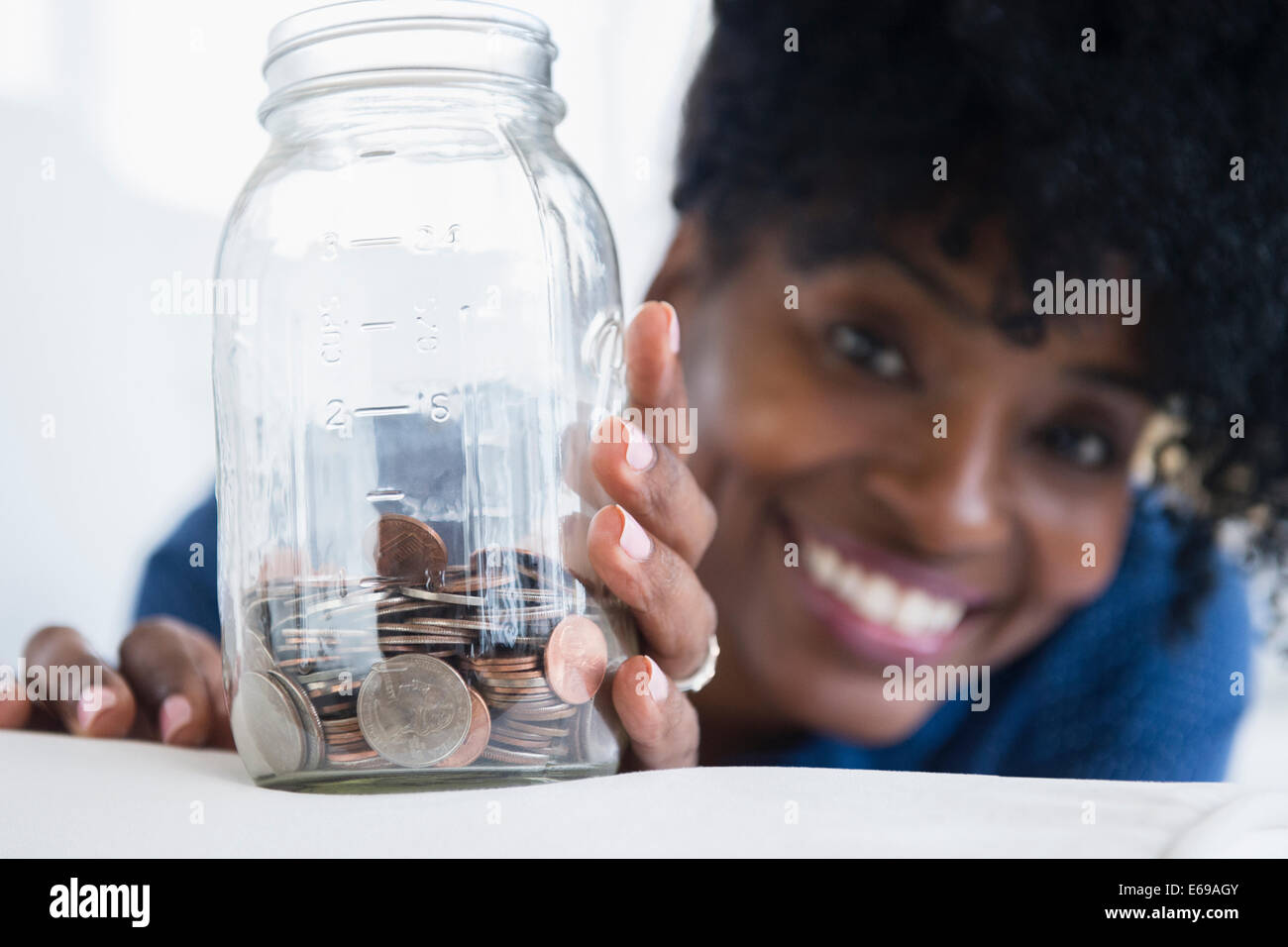 Nero donna salvataggio di monete in vaso Foto Stock