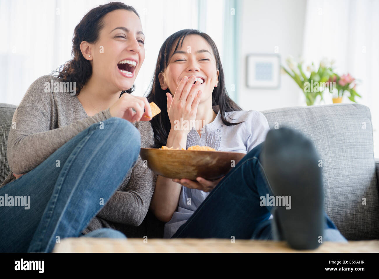 Le donne ridere sul divano insieme Foto Stock