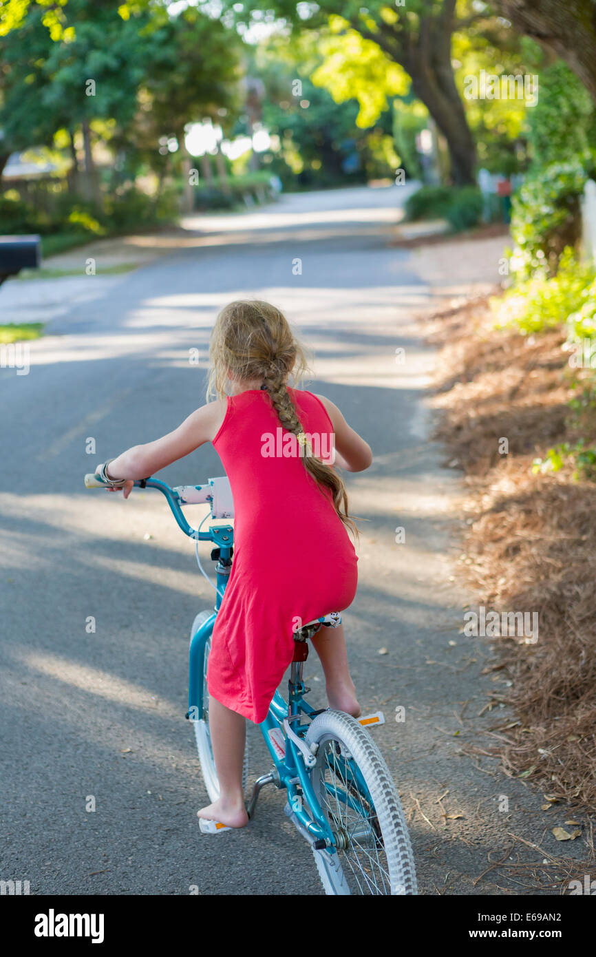 Ragazza caucasica equitazione bicicletta su strada Foto Stock