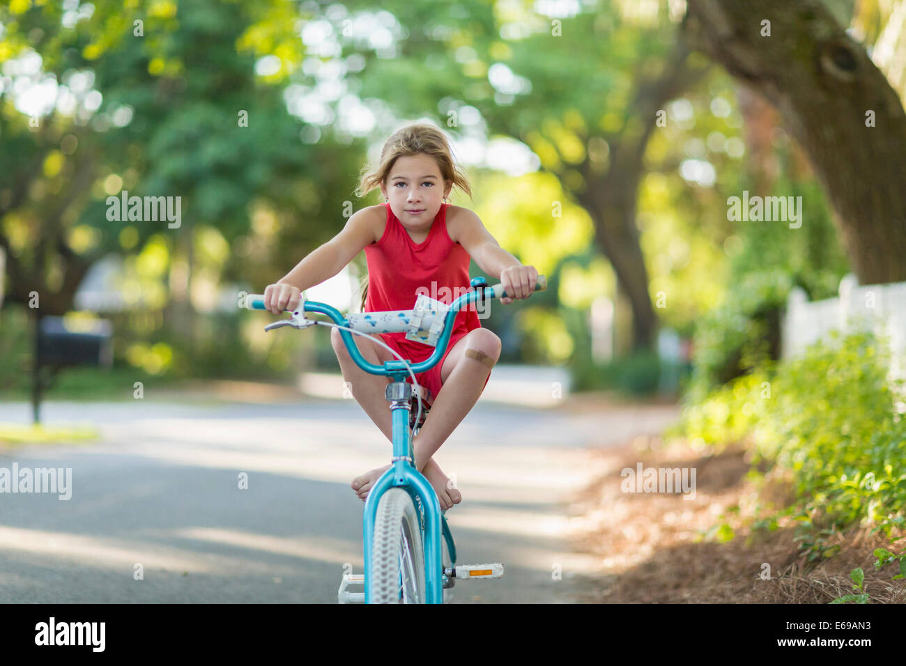 Ragazza caucasica equitazione bicicletta su strada Foto Stock