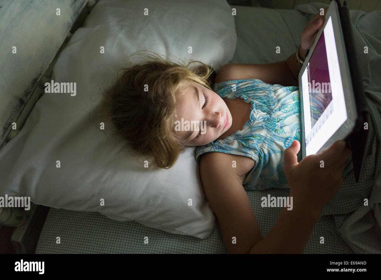 Ragazza caucasica utilizzando computer tablet a letto Foto Stock