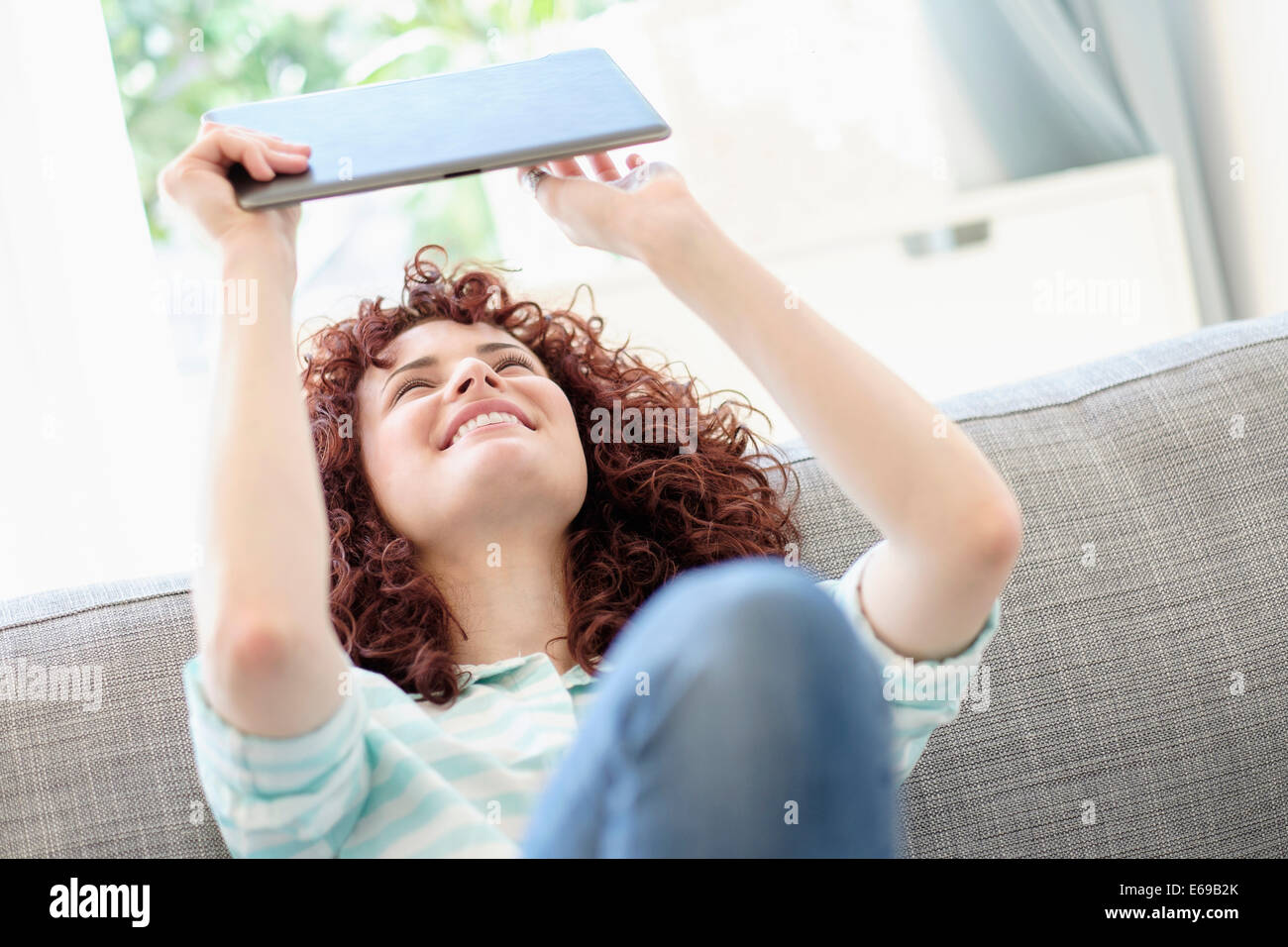 Donna ispanica con tavoletta digitale sul divano Foto Stock