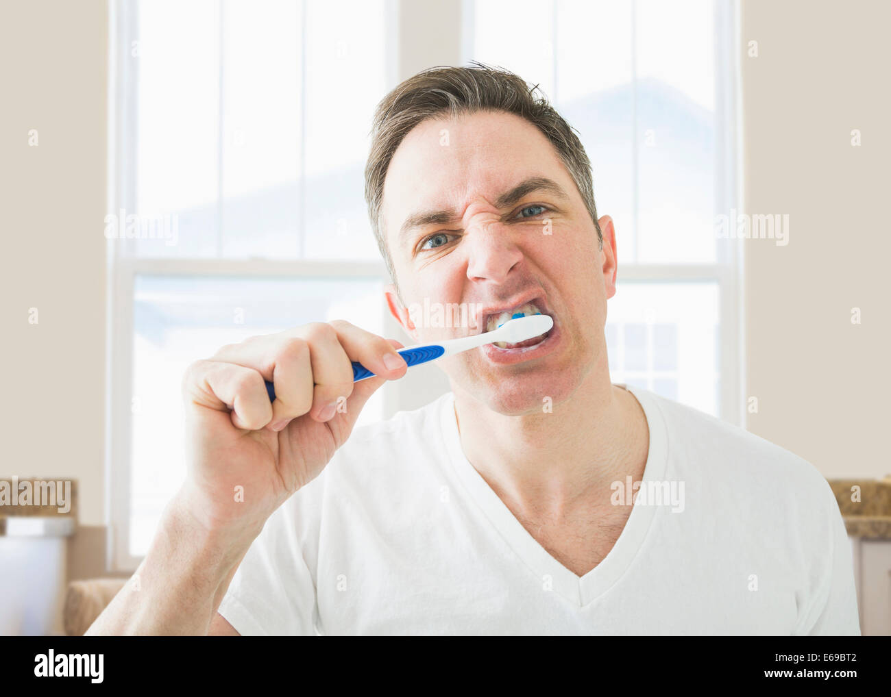 Caucasian spazzolando i suoi denti nella stanza da bagno Foto Stock