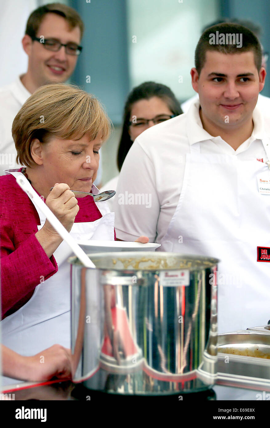 Bonn, Germania. 19 Ago, 2014. Il cancelliere tedesco Angela Merkel (C) suscita uno stufato in una cucina di campo dell'Ordine di San Giovanni di Bonn, Germania, 19 agosto 2014. Il cancelliere tedesco ha visitato l'Ufficio federale della protezione civile e di assistenza di emergenza per conoscere il lavoro di ufficio e dell'Agenzia federale per il rilievo tecnico (THW). Foto: OLIVER BERG/DPA/Alamy Live News Foto Stock