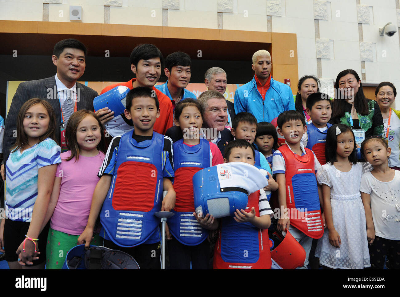 Nanjing, Cina. 19 Ago, 2014. Il presidente del Comitato Olimpico Internazionale Thomas Bach(C) pone con il personale e i bambini al Centro Expo Internazionale in Nanjing, a est della capitale cinese della provincia di Jiangsu, 19 Agosto, 2014. Credito: Xinhua/Alamy Live News Foto Stock