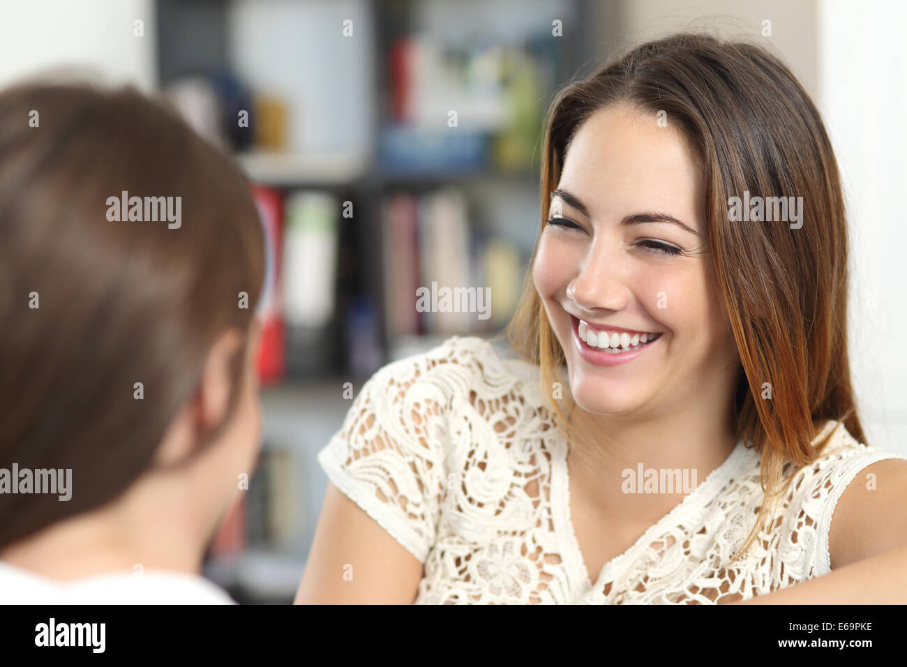 Donna felice tenendo una conversazione e ridere con un amico a casa Foto Stock