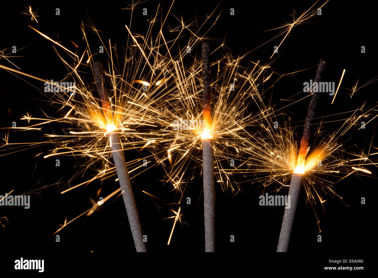 Tre brucianti gold fuochi d' artificio botti emettendo scintille contro uno sfondo nero. Foto Stock