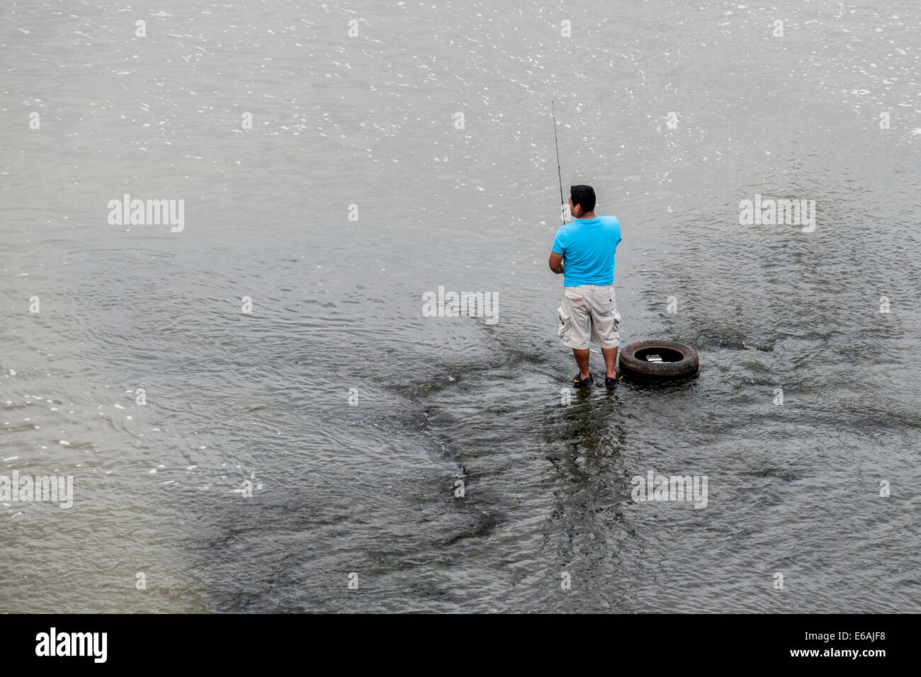 Un uomo ispanico pesci in acqua al di sotto di una diga in Oklahoma, Stati Uniti d'America. Foto Stock
