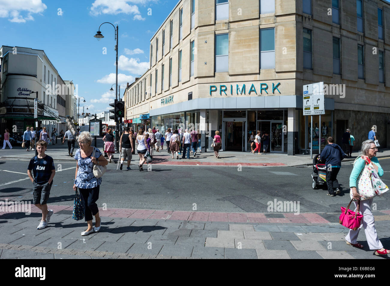 Gli amanti dello shopping attraversando la strada al di fuori di Primark in Cheltenham town center Foto Stock