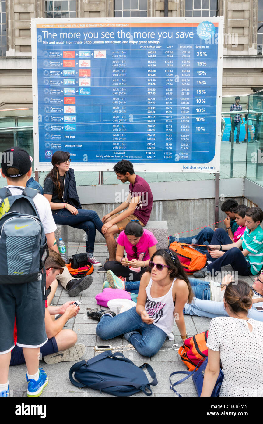 Giovani turisti stranieri rilassarsi di fronte ad una tariffa segno per Londra Attrazioni principali Foto Stock