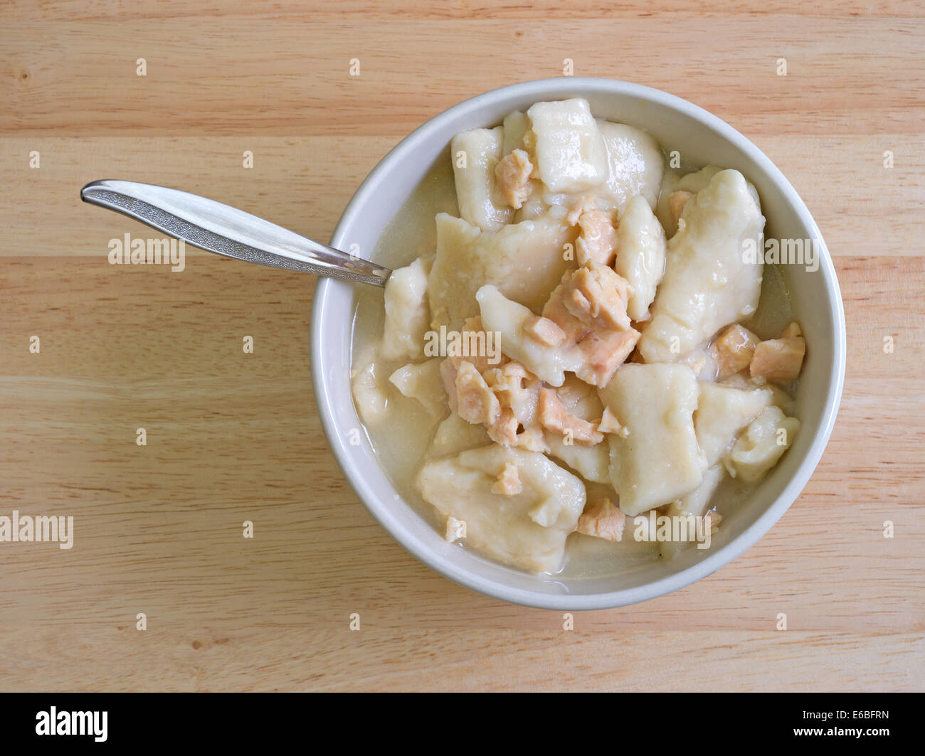 Vista dall'alto di una ciotola di pollo e gnocchi di patate Zuppa con il cucchiaio su una tavola di legno alto. Foto Stock