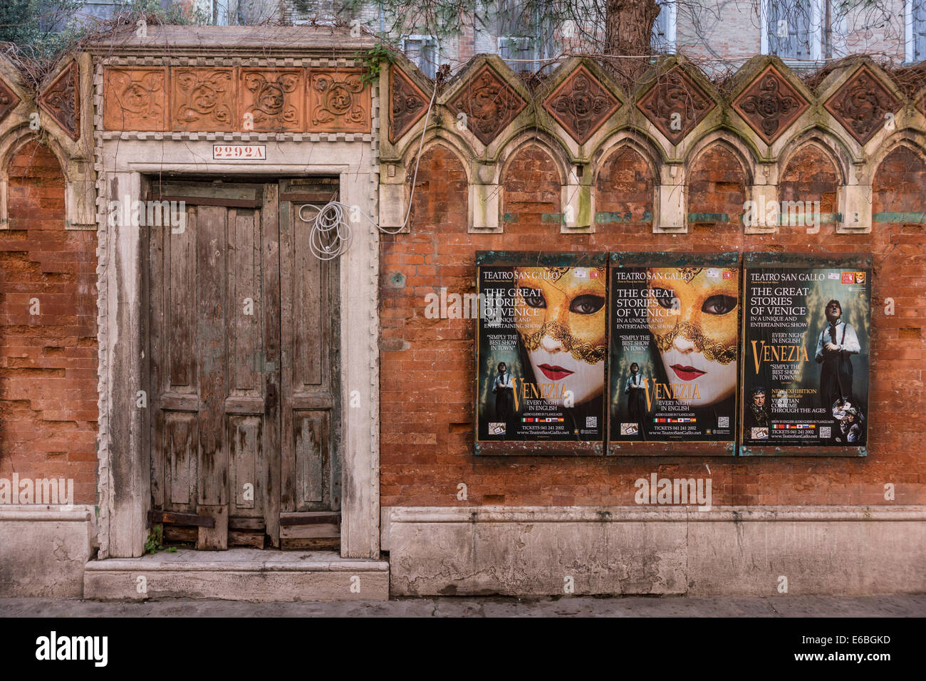 Il vecchio muro di mattoni con legno porta ingresso mostra poster di un notturno prestazioni turistiche di Venezia. Foto Stock