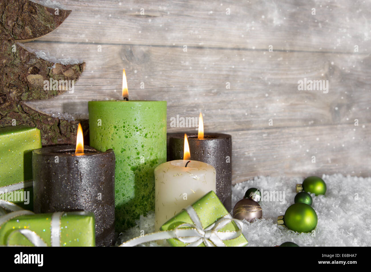 Quattro burning avvento candele in verde e marrone in legno su sfondo grigio. Foto Stock