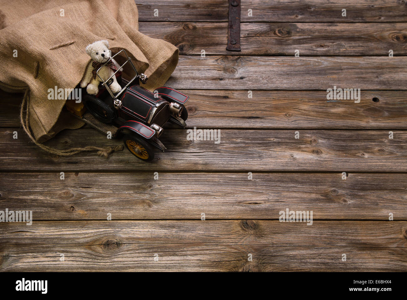 Vecchio legno background: decorazione di Natale con il vecchio orsacchiotto di peluche e una vettura di stagno. Foto Stock