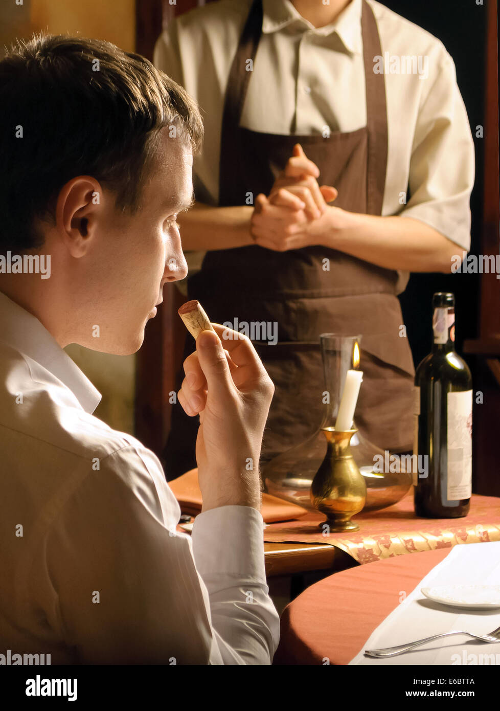 Giovane uomo annusando il tappo di una bottiglia di vino Foto Stock