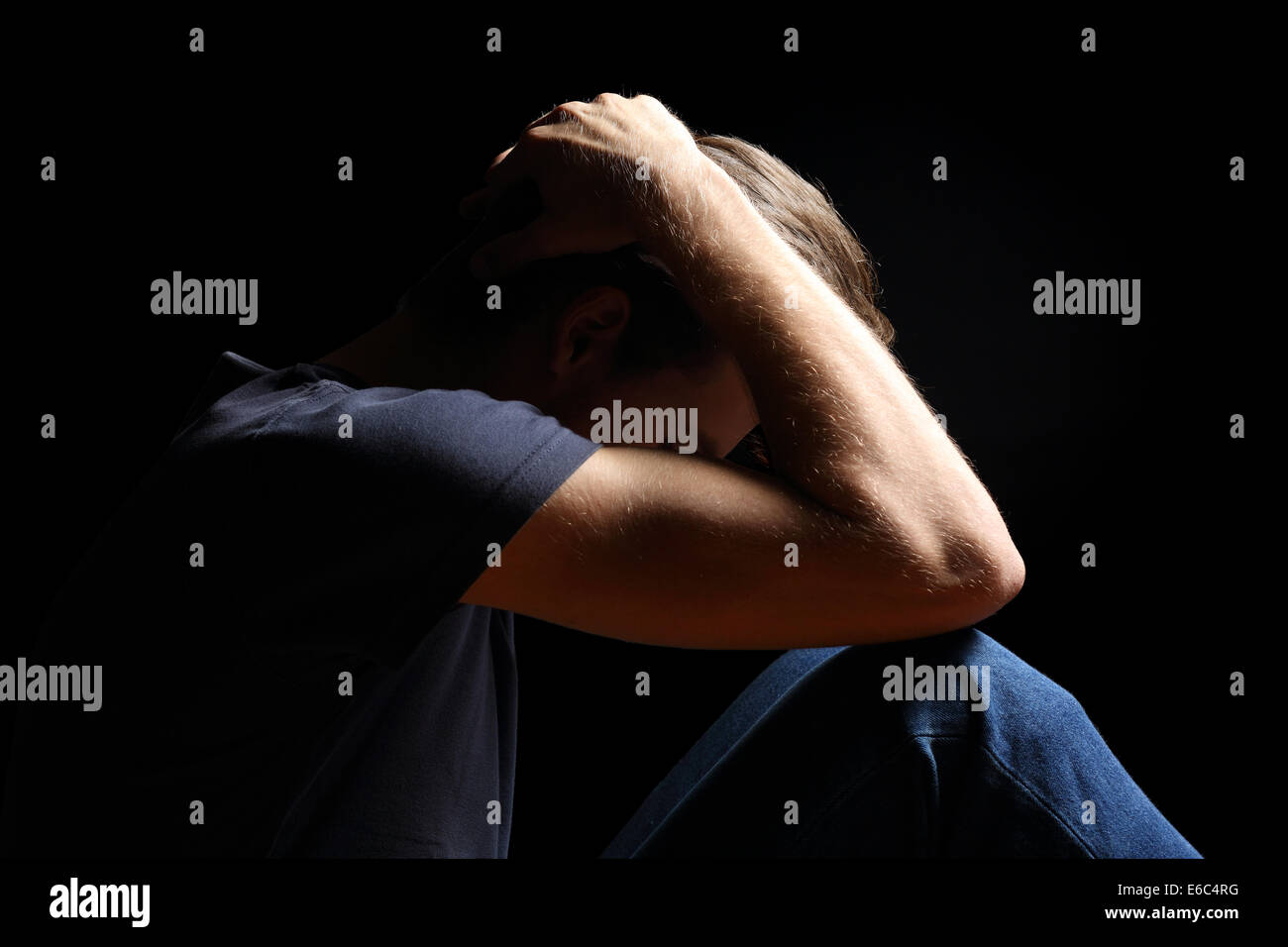 Premuto adolescente uomo con le mani sopra la testa isolato in uno sfondo nero Foto Stock