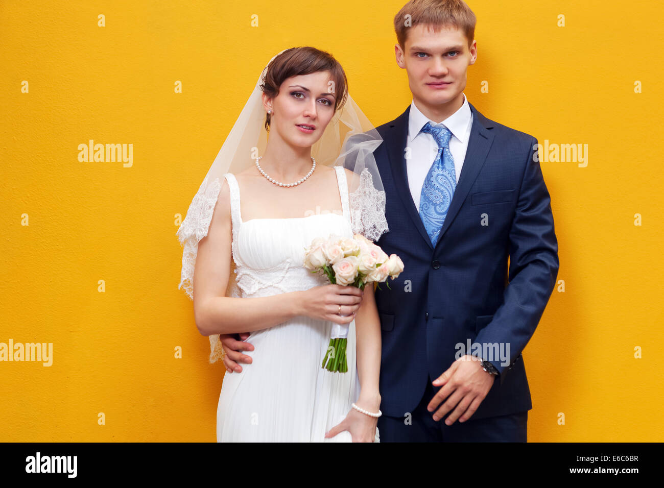 Sposa e lo sposo in piedi contro la parete gialla Foto Stock