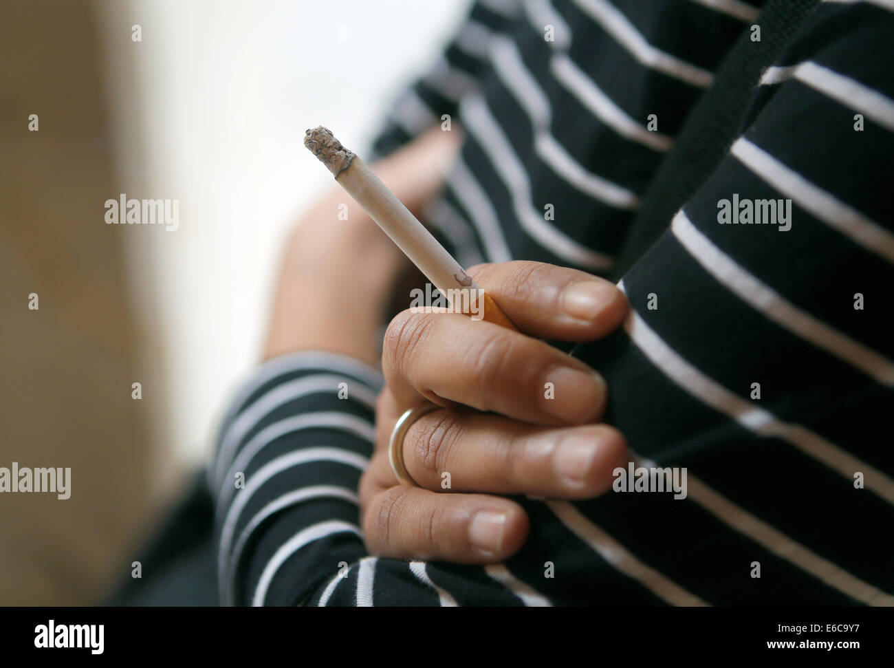 Una donna in possesso di una sigaretta sulla sua dita Foto Stock