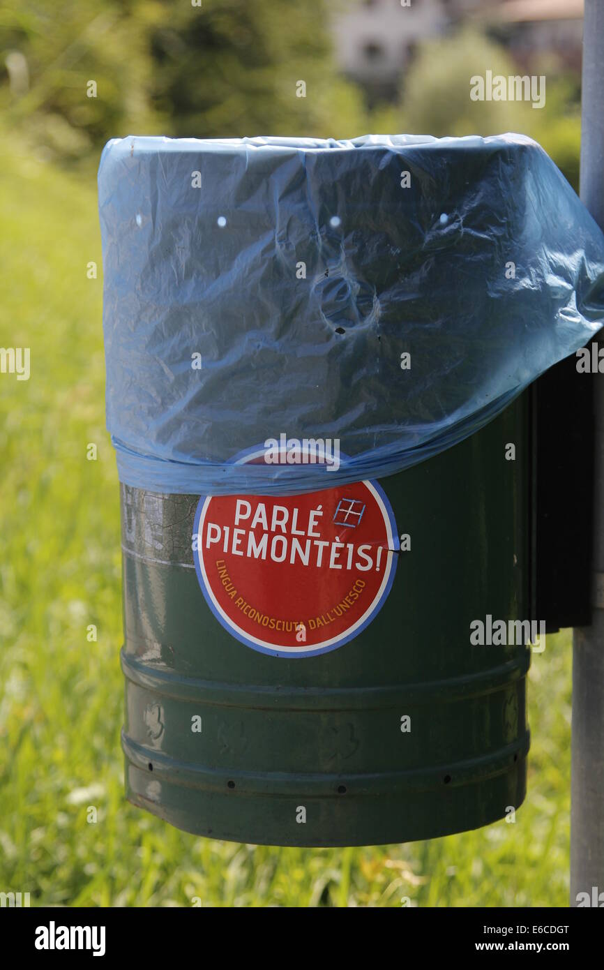 Bidone della spazzatura in Italia, con un adesivo che invita la gente a parlare in piemontese, il dialetto locale di Torino e Piemont. Foto Stock