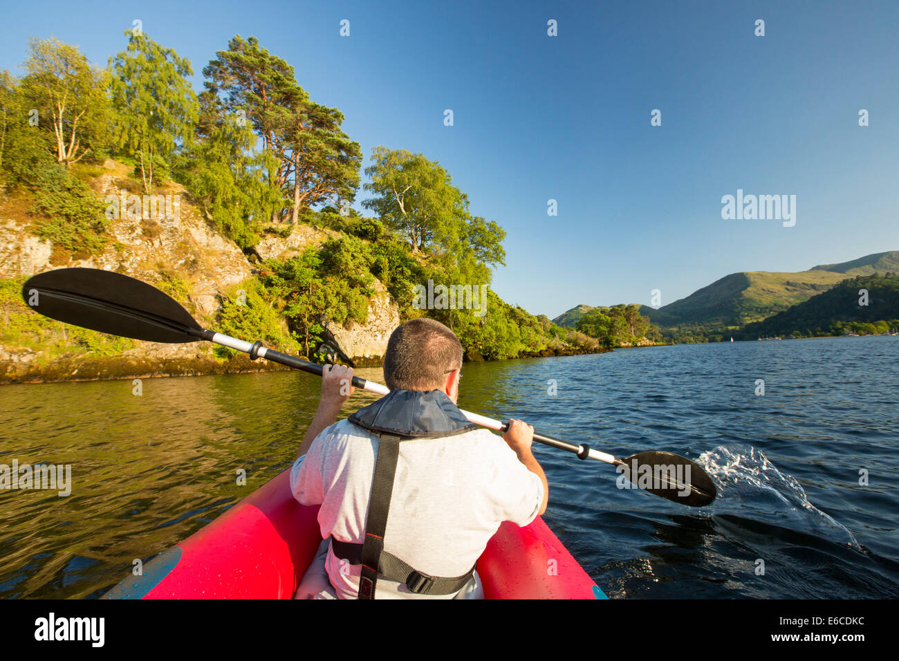 Un uomo di mezza età paddling in un kayak inflateable sull'Ullswater nel distretto del lago, UK. Foto Stock