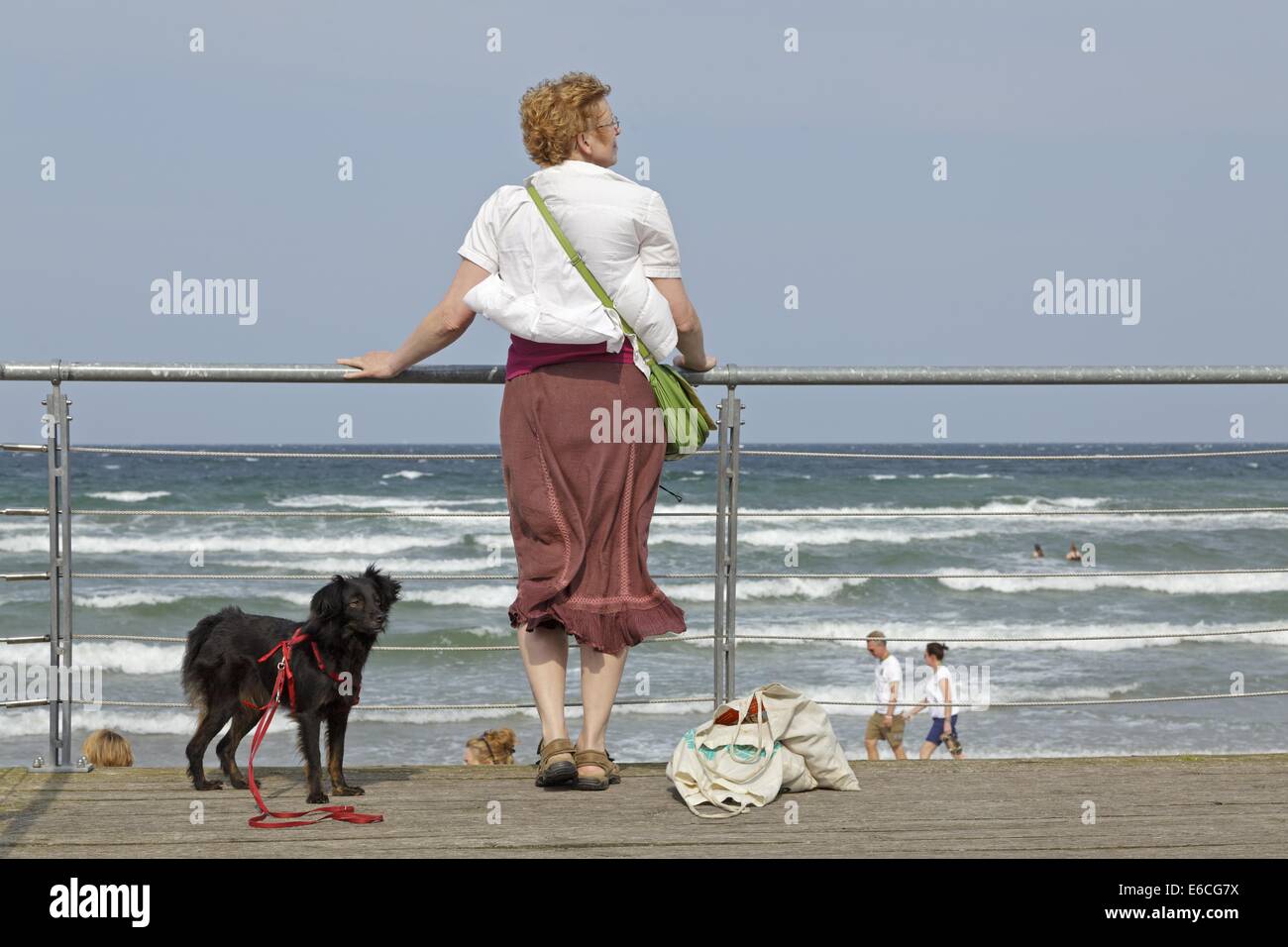 Donna con cane guardando al di là del mare, Scharbeutz, Schleswig-Holstein, Germania Foto Stock
