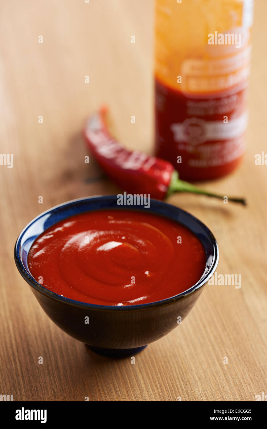 Ciotola e bottiglia di salsa sriracha Foto Stock