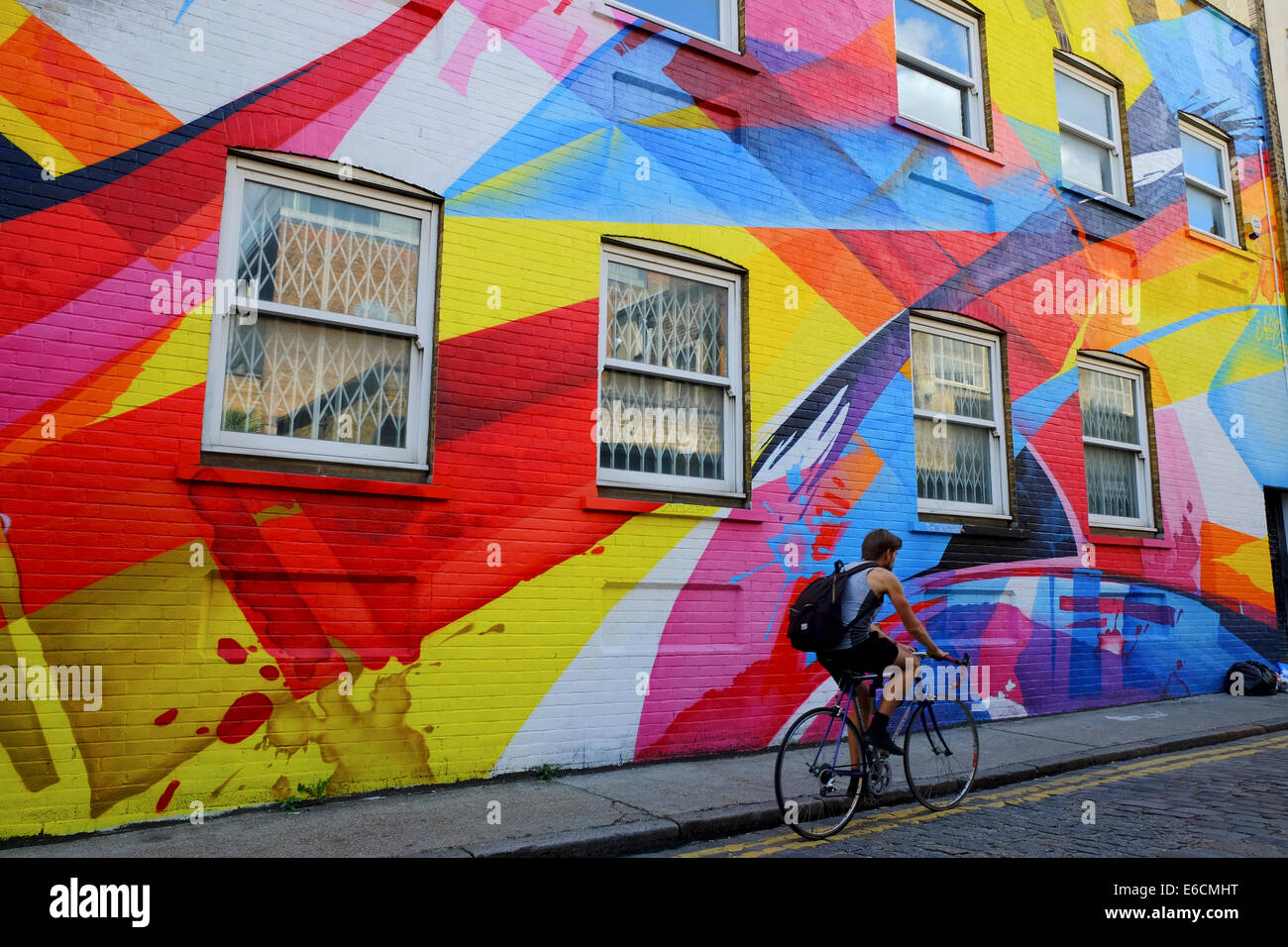 Pedalando attraverso il coloratissimo graffito in Shoreditch, Londra, UK (solo uso editoriale) Foto Stock