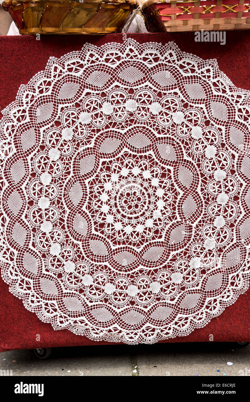 Intricato round tovaglia di pizzo contro uno sfondo di colore rosso sull'isola di Burano nella Laguna veneziana. Foto Stock