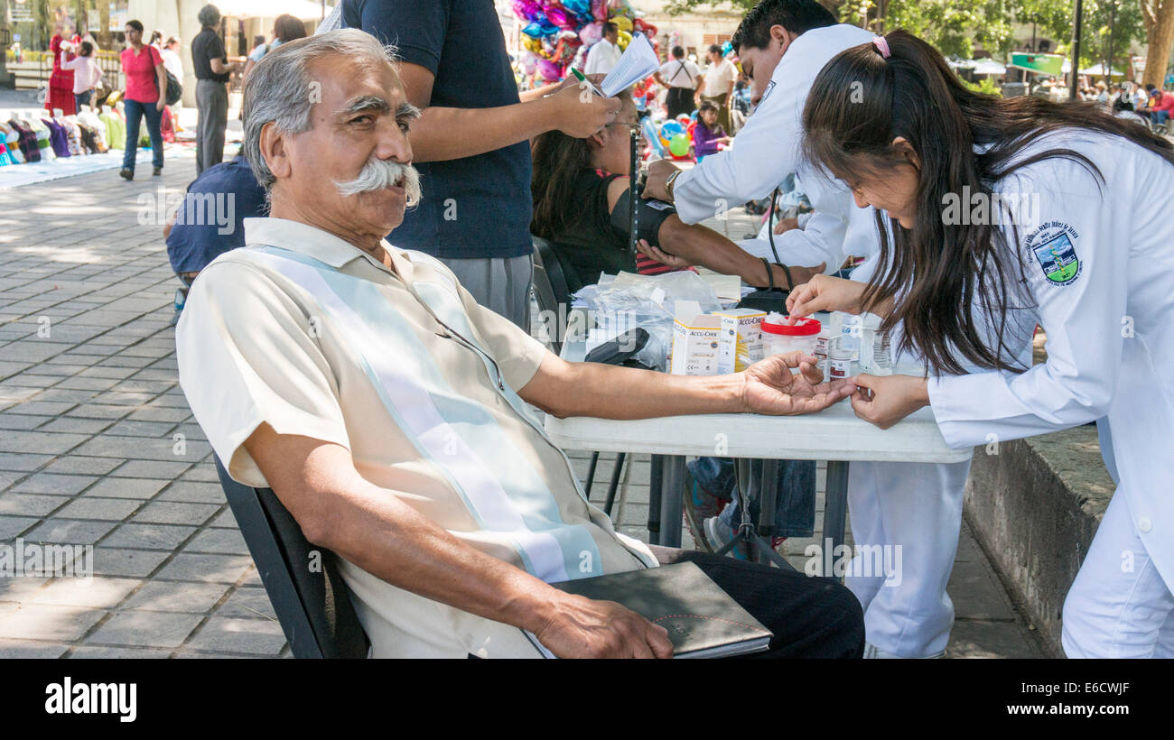 Il vecchio uomo con magnifici baffi bianchi si prepara a hanno dito punga per la prova del diabete a free public health clinic all'aperto Foto Stock