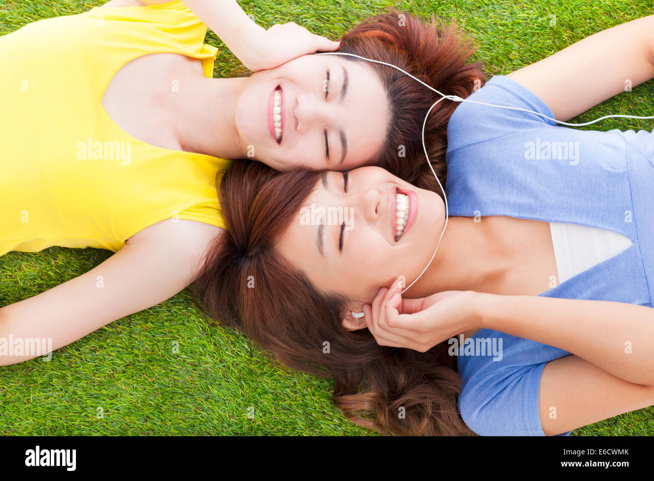 Due piuttosto giovane donna sdraiata su pascoli e ascolto di musica Foto Stock