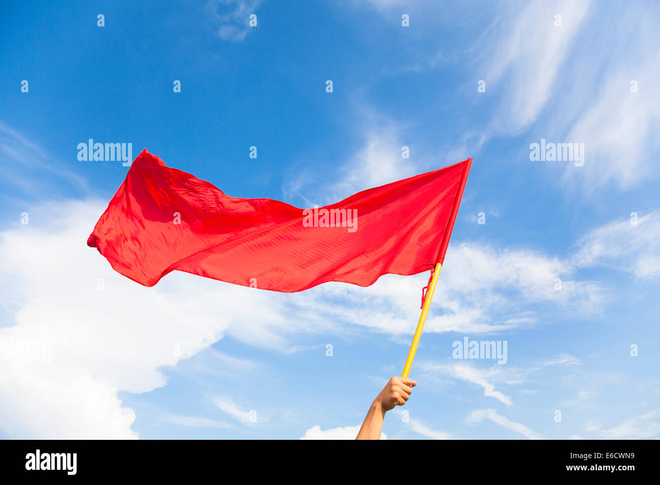Mano sventola una bandiera rossa con cielo blu sullo sfondo Foto Stock