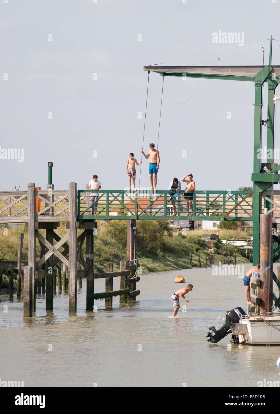 Giovani jumping off bridge Le port du Plomb, L'Houmeau, Francia Foto Stock