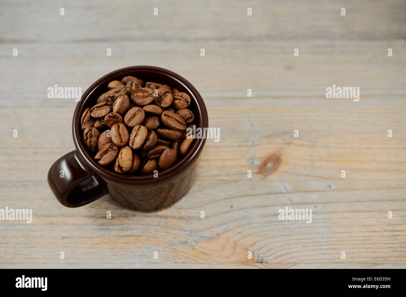 Tazza marrone con chicchi di caffè su sfondo di legno Foto Stock