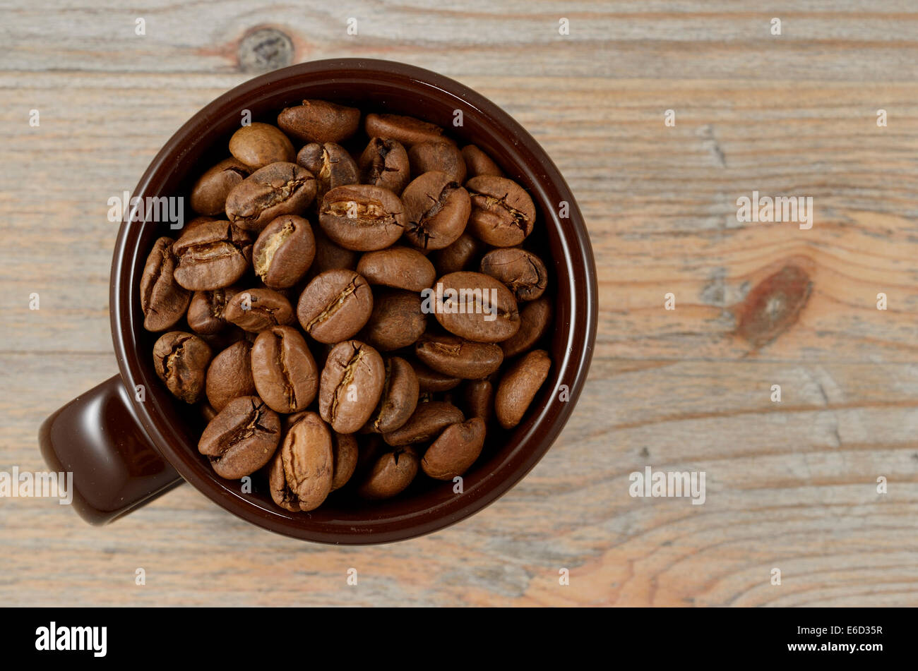Tazza marrone con chicchi di caffè su sfondo di legno Foto Stock