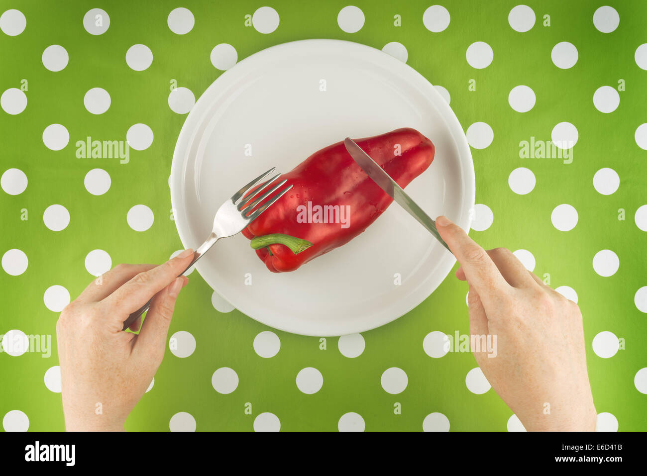 Donna di mangiare crudo fresco pepe rosso su una piastra bianca, vista dall'alto. Foto Stock