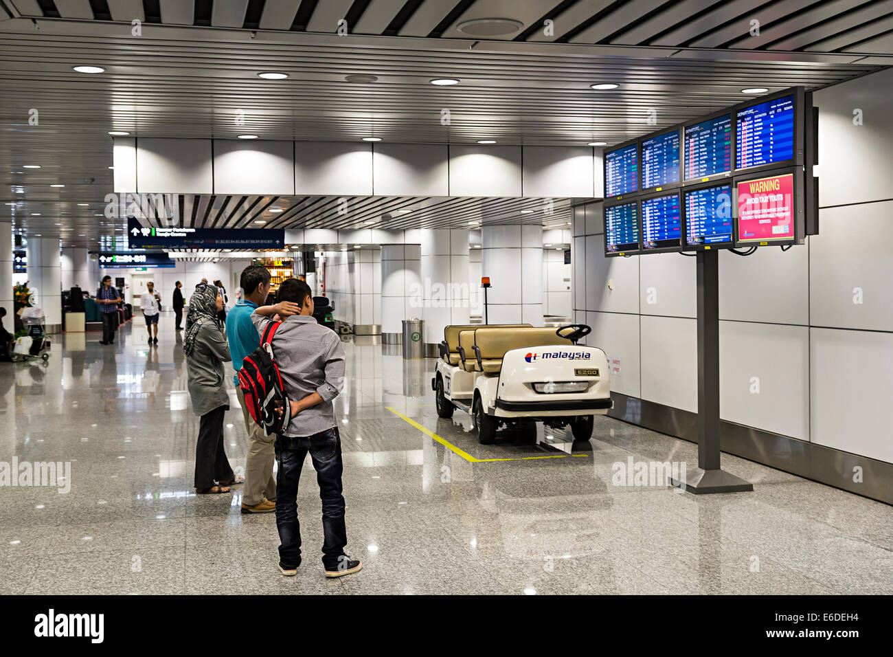 Persone in transito guardando a schermate di informazioni in aeroporto, Miri, Malaysia Foto Stock
