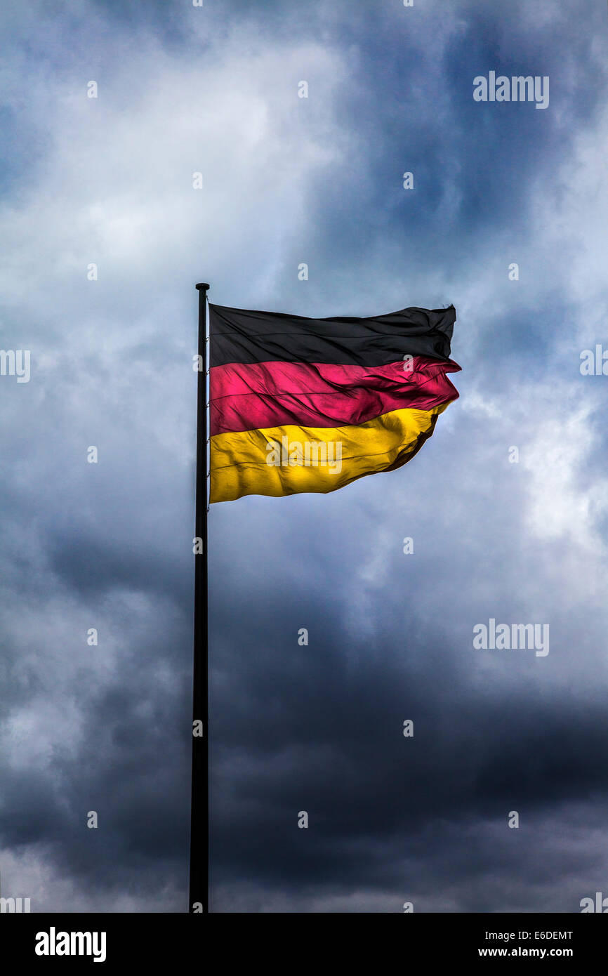 Nuvole temporalesche raccolta dietro la bandiera tedesca, simbolico della crisi politica, la guerra o disordini. Foto Stock