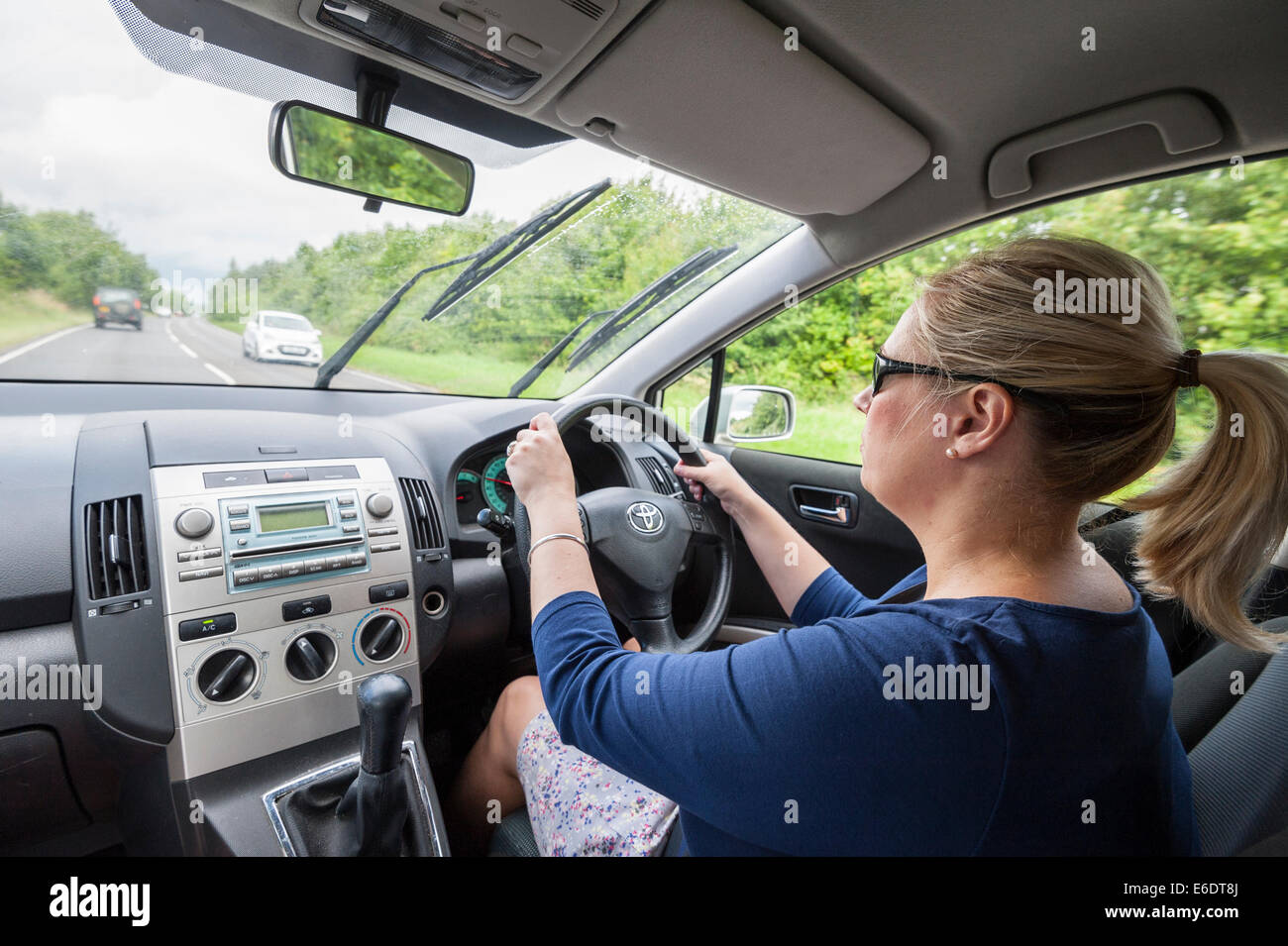 Una donna alla guida illustrata dall'interno della vettura nel Regno Unito Foto Stock
