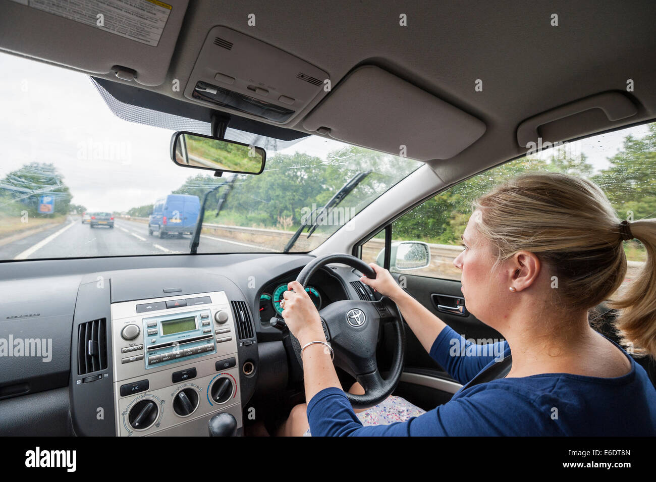 Una donna alla guida illustrata dall'interno della vettura nel Regno Unito Foto Stock