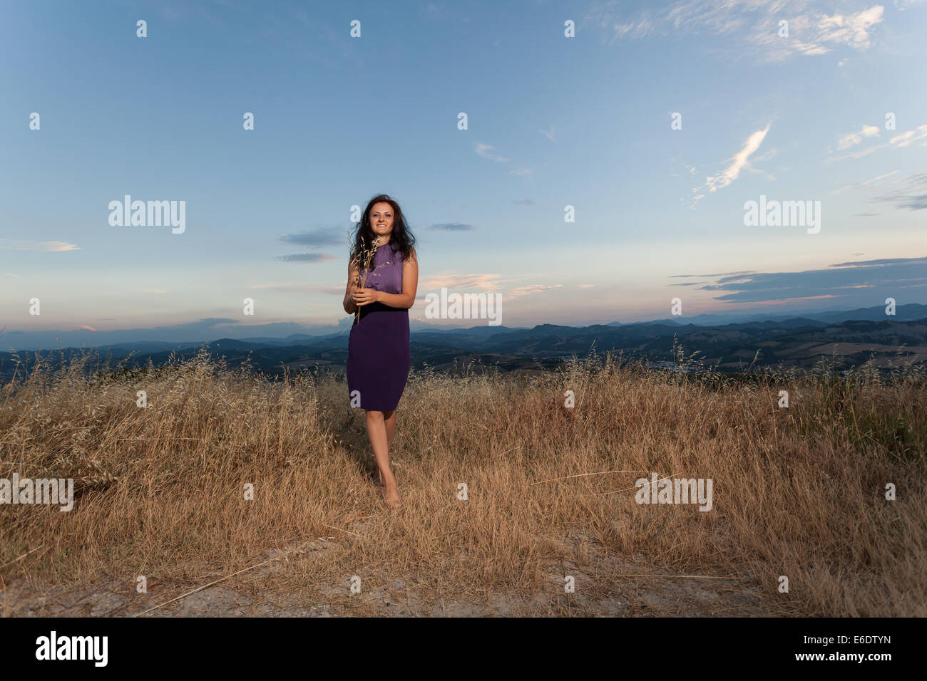 La donna caucasica in abito viola in campo Foto Stock