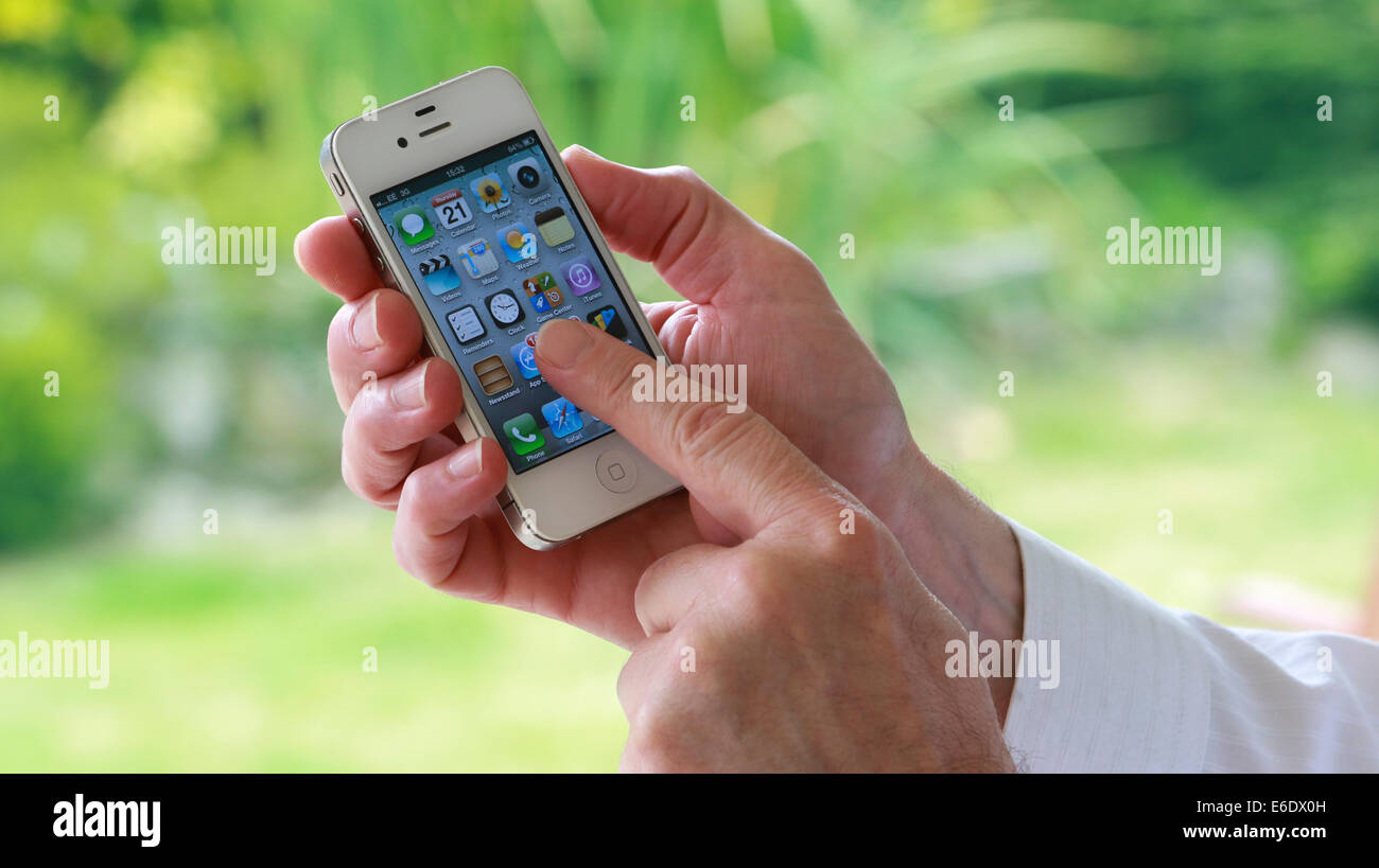 Una mano d'uomo in possesso di un i-phone premendo un app sullo schermo. Foto Stock