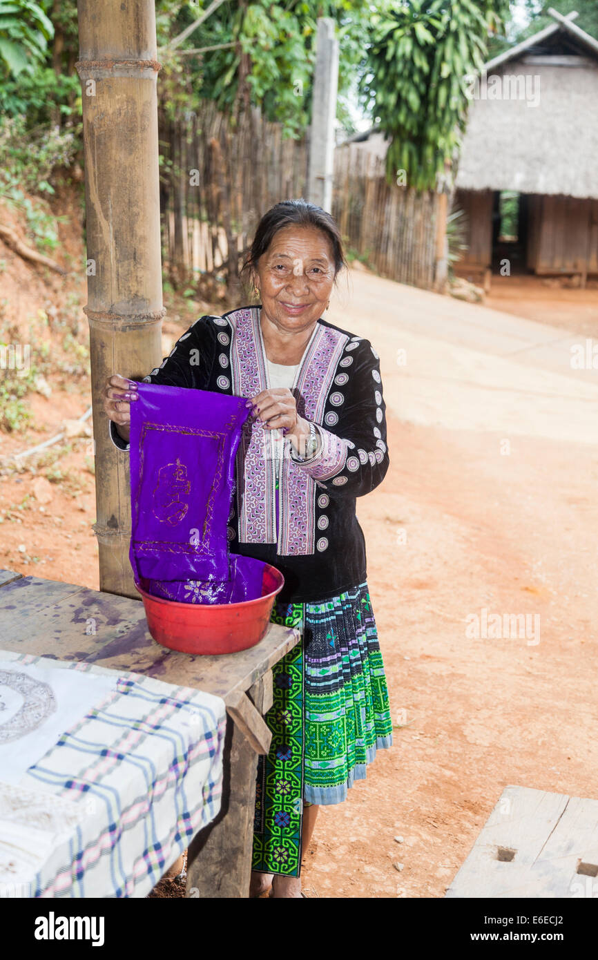 Hmong vecchia donna nel tradizionale colorato abito locale a dimostrazione della realizzazione dei Batik, Chiang Khong, provincia di Chiang Rai, Thailandia Foto Stock
