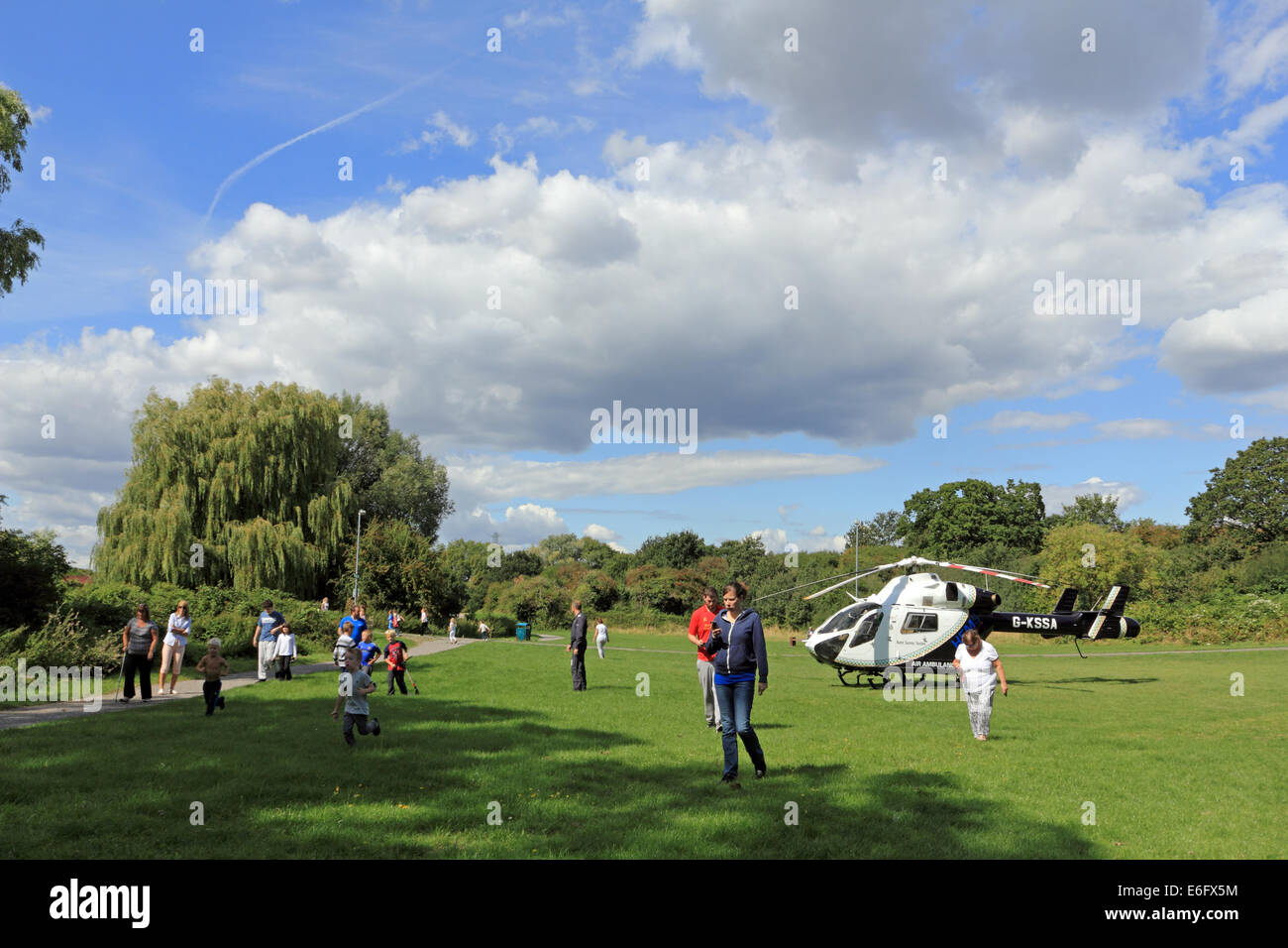 West Ewell, Epsom Surrey, Regno Unito. Il 22 agosto, 2014. I residenti di West Ewell ha avuto una sorpresa questo pomeriggio come KSSA (Kent Surrey Sussex Air Ambulance) è atterrato su una zona del Hogsmill spazio aperto tra il Riverview scuola e la Watersedge station wagon. È atterrato alle ore 13.30 in risposta a 'una emergenza medica" dell'azienda. I locali si sono riuniti per vedere il sito insolito di un elicottero così vicino alla scatola nelle vicinanze, e come era estate tempo di vacanza molti curiosi i bambini erano desiderosi di testimoniare l'evento. Credito: Julia Gavin UK/Alamy Live News Foto Stock