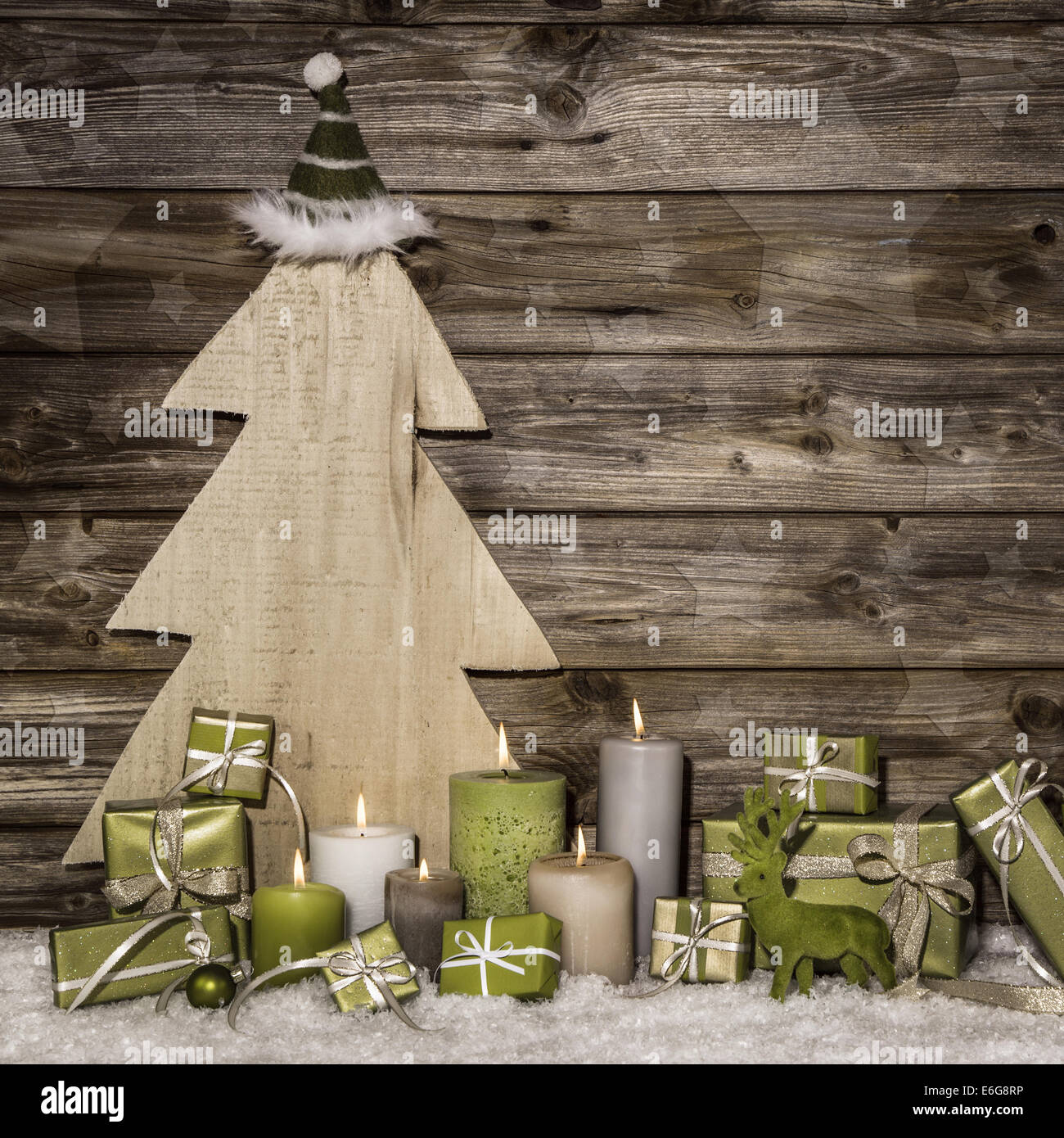Naturale natale decorazione in verde e marrone su sfondo di legno con presenta e candele accese. Foto Stock