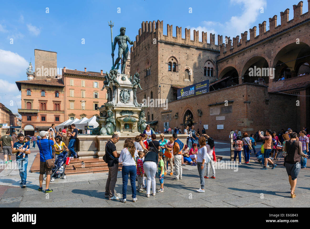 I turisti si sono riuniti intorno alla fontana di Nettuno con il Palazzo di Re Enzo dietro Piazza del Nettuno, Bologna, Emilia Romagna, Italia Foto Stock