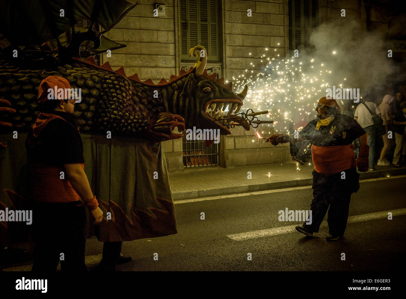 Un membro di 'la Vella de Gràcia' lits draghi petardi durante il 'Correfocs' a 'Festa Major de Gracia'. © matthi/Alamy Live News Foto Stock