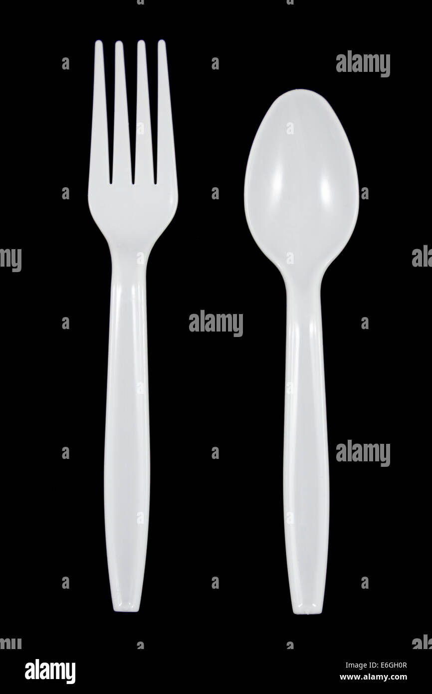 In plastica bianca cucchiaio e forchetta su sfondo nero. Foto Stock